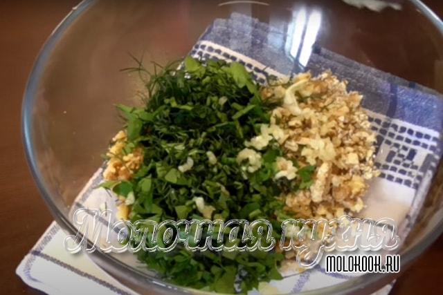 Зелень, ядра орехов и измельченные чесночные зубчики в миске