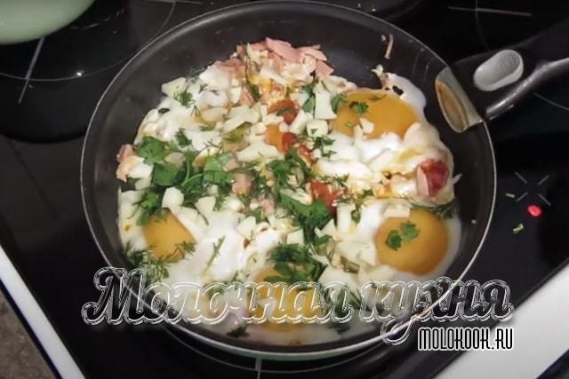 Яичница посыпана измельченным сыром и зеленью